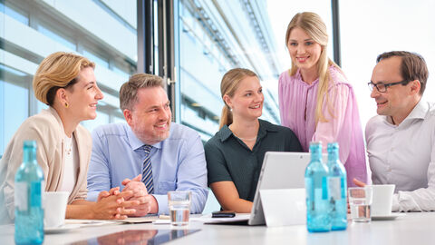 Eine Gruppe von Personen sitzt an einem Schreibtisch in einem Besprechungsraum.